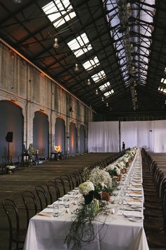 a long table set up for a wedding with white flowers and place settings on it