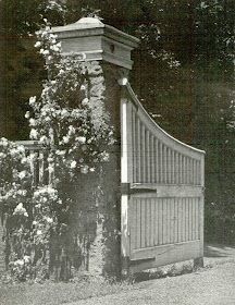 an old black and white photo of a gate in the middle of a garden with flowers growing on it