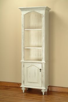 an old white china cabinet in the corner of a room with wood floors and walls