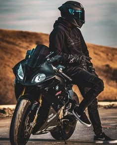 a man sitting on the back of a motorcycle wearing black leather pants and a helmet