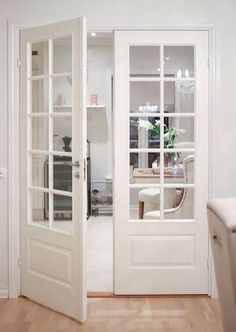 an open door leading into a white room with pictures on the wall and wooden floors