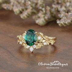 a close up of a ring with a green stone on the top and white diamonds around it