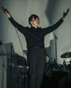 a man standing on top of a stage holding his arms in the air with one hand