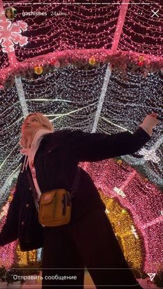 a woman standing in front of a christmas light display with her arms spread out to the side