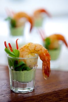 small cups filled with shrimp and garnish on top of a wooden table