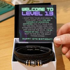 a person holding up a birthday card in a box with two bracelets on it