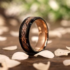 a wedding ring with an intricate design on it sitting on a wooden table surrounded by petals