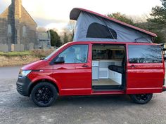 a red van parked in front of a church with its doors open and the roof opened