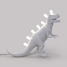 a toy dinosaur with white lights on it's back legs and head, standing in front of a gray background