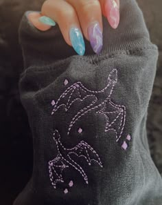 a woman's hand with painted nails holding onto a gray sweater that has an image of a horse on it