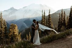 a bride and groom standing on top of a mountain