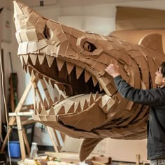 a man standing next to a cardboard model of a large alligator's head with sharp teeth