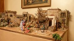 a nativity scene with figurines in front of a painting on the wall