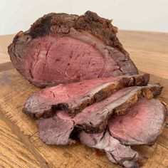 sliced roast beef sitting on top of a wooden cutting board