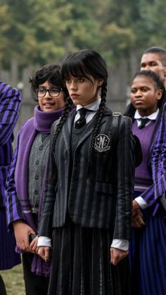 a group of people standing next to each other wearing purple and black outfits with long braids