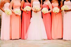 a group of women standing next to each other wearing dresses and holding bouquets in their hands