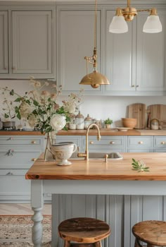 a kitchen island with two stools in front of it and flowers on the counter