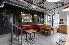 the interior of a restaurant with tables and chairs, chalkboard on the wall, and wooden benches