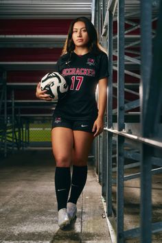 a female soccer player is holding a ball and posing for a photo in the locker room