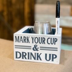 a sign that says mark your cup and drink up with a pen in the holder