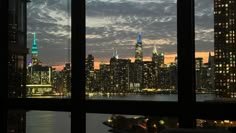 the city skyline is lit up at night as seen from an apartment window in new york's financial district