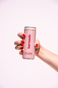 a woman's hand holding a can of pink soda