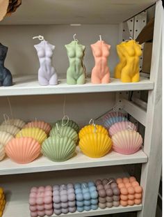 there are many different colored candles on the shelves