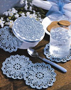 crocheted doily and plates on a wooden table with flowers in the background