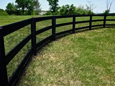 a black fence in the middle of a grassy field