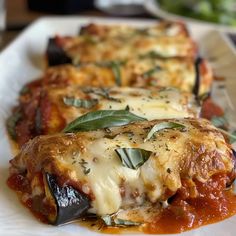 three slices of lasagna on a plate with sauce and basil garnish