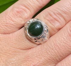 Recently acquired from a jeweler's estate comes this beautifully finished man's statement ring featuring a genuine cabochon-cut, 14 x 12mm oval, bezel-set dark green Nephrite Jade gemstone. The ring is crafted of solid sterling silver .925 and weighs 9.0 grams. It has a scroll design on the sides. It is a finger size 11, but can be sized (please inquire for sizing charge). This ring was part of the jeweler's store stock and has been in a vault since the jeweler's store closed in the mid 1980's. The shank is marked 925. Gold Rosary Necklace, Silk Cord Necklace, Moldavite Jewelry, Jade Gemstone, Nephrite Jade, Statement Ring Silver, Jade Ring, Mens Silver Rings, Scroll Design