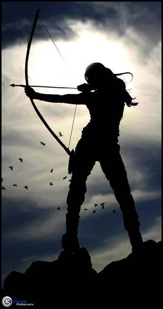 the silhouette of a person with a bow and arrow in front of a cloudy sky