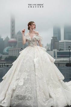 a woman in a white wedding dress standing on top of a bridge with her hands up