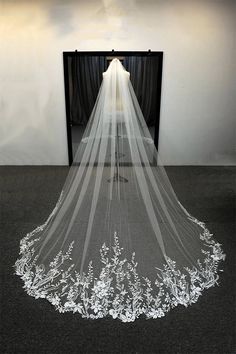 a wedding veil with white flowers on the bottom is hanging in front of a mirror