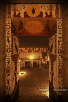 the entrance to an egyptian temple at night with lights on and paintings on the walls