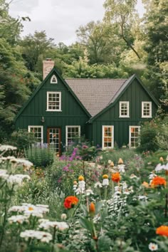 a green house surrounded by flowers and trees