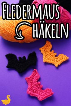 three crocheted bats and two skeins of yarn on a purple surface