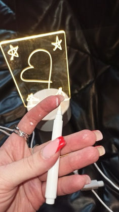 a person holding a white pen in their left hand with a gold playing card on it