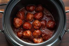 a crock pot filled with meatballs on top of a wooden table