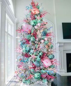 a decorated christmas tree in the middle of a living room with white walls and windows