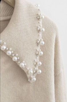 a white sweater with pearls on the collar