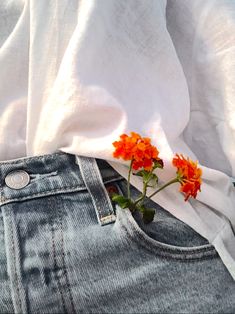 an orange flower sticking out of the back pocket of someone's jeans