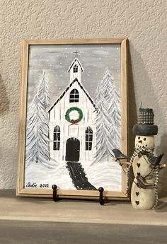 a snowman is next to a painting on the mantle in front of a house