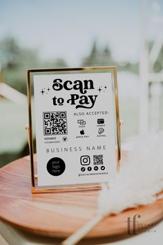 a scan to pay sign sitting on top of a wooden table next to a white feather