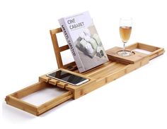 a wooden tray with a cell phone and magazine on it, next to a glass of wine