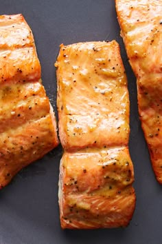 four pieces of cooked salmon on a black plate