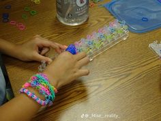 two hands are holding plastic beads on a table