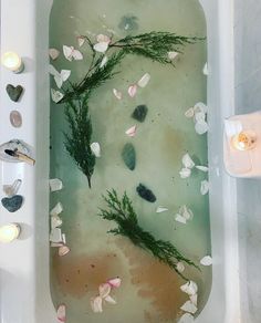 a bathtub filled with lots of water next to candles and flowers on the floor