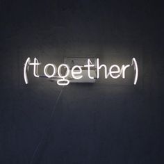 a neon sign that says together on it's side, in the middle of a dark room