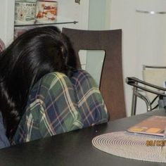 two people sitting at a table with their backs to each other and one person holding his head